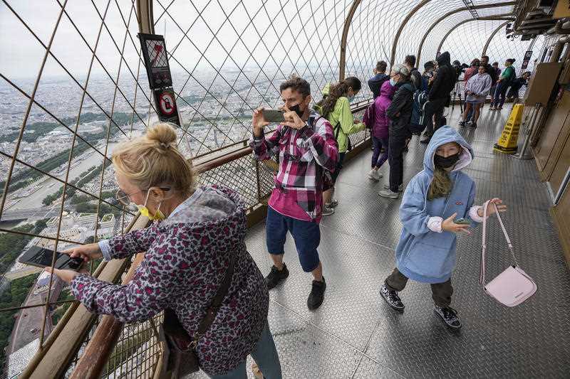 , visitors enjoy the view from top of the Eiffel Tower in Paris