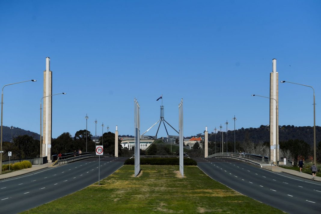 A deserted Commonwealth Avenue, three lanes in each direction, looking towards Australian Parliament House in Canberra