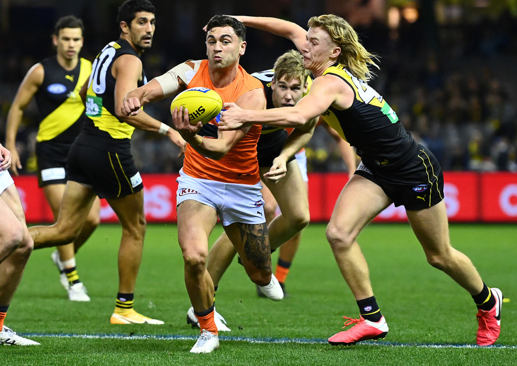 MELBOURNE, AUSTRALIA - MAY 15: Tim Taranto of the Giants handballs whilst being tackled by Hugo Ralphsmith of the Tigers during the round 9 AFL match between the Richmond Tigers and the Greater Western Sydney Giants at Marvel Stadium on May 15, 2021 in Melbourne, Australia. (Photo by Quinn Rooney/Getty Images)