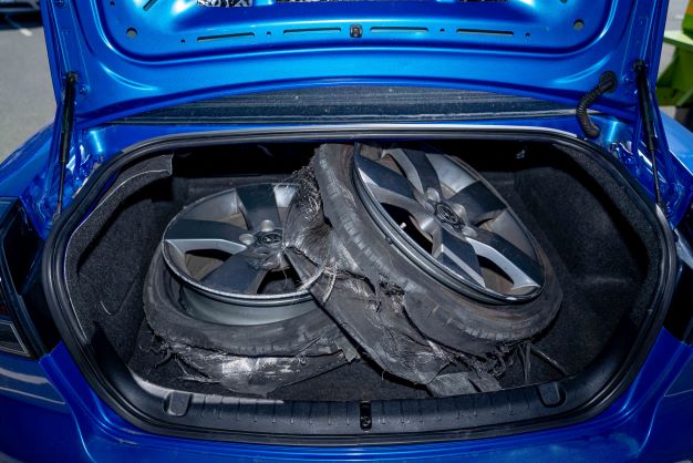 boot of blue Holden commodore with burnt out tyres inside