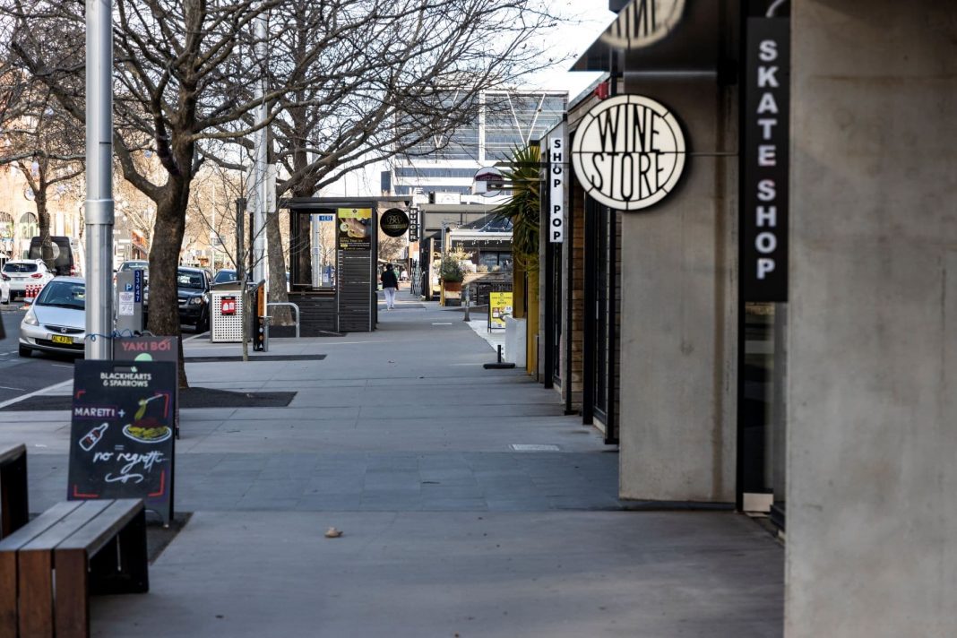 one lone pedestrian is seen walking down a normally busy high street that is deserted during lockdown in Canberra