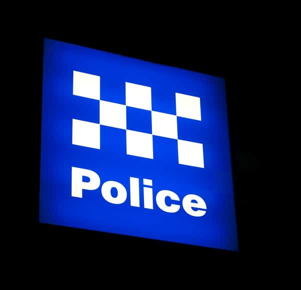 An Australian Police sign lit at night against a black sky