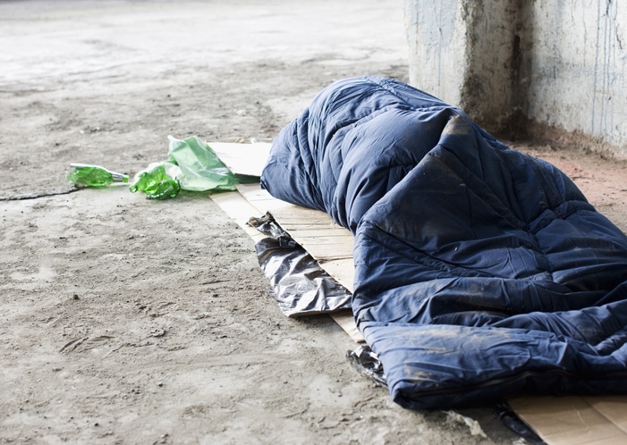 Homeless person sleeping in sleeping bag on cardboard on the streets