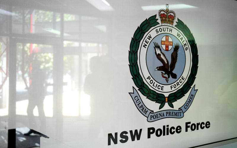 NSW Police Force insignia seen on side of white police vehicle