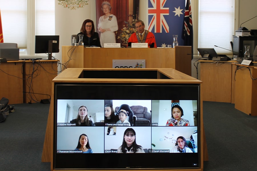 six people on Zoom call at virtual citizenship ceremony as two people look on in council chambers