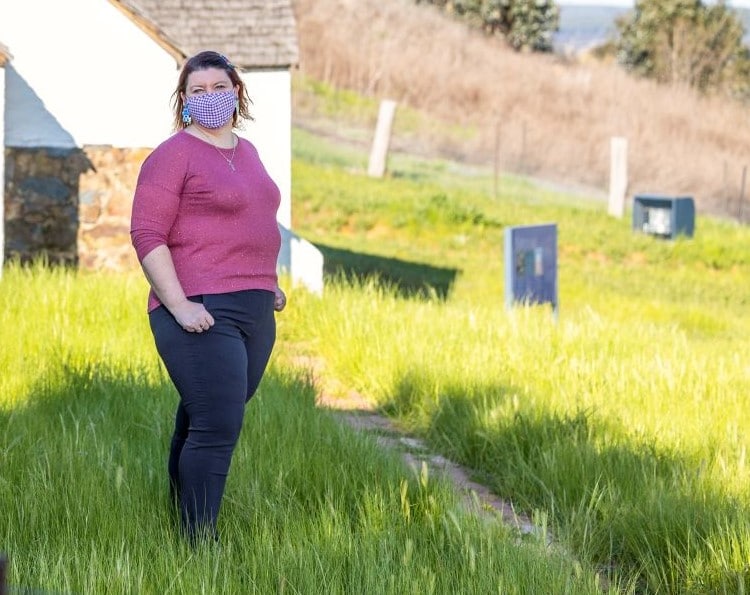 woman wearing a face mask is seen standing outside in the sunshine to promote Mental Health Month