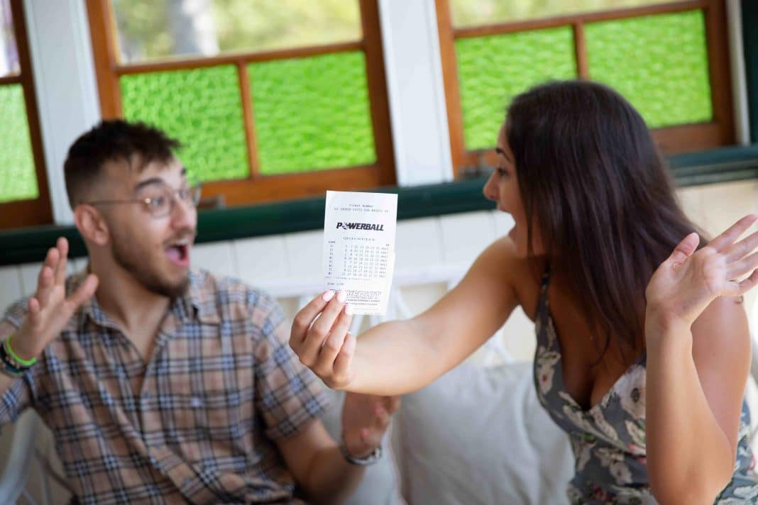 young couple holding winning lottery ticket