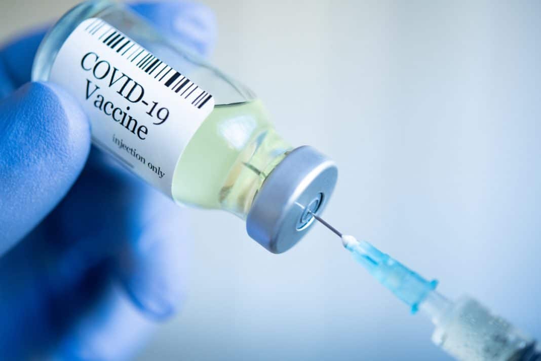 a needle is seen entering a COVID-19 vaccine vial
