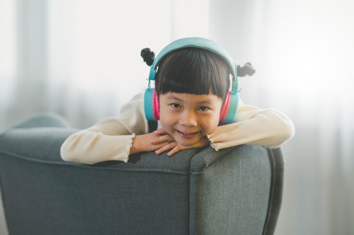 Image of Young Asian girl with headphones on at home