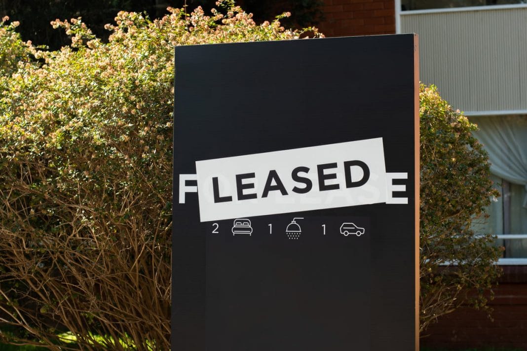 Image of LEASED house sign in front of a green hedge