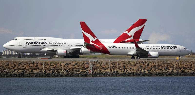 two Qantas planes taxi on the runway at Sydney Airport