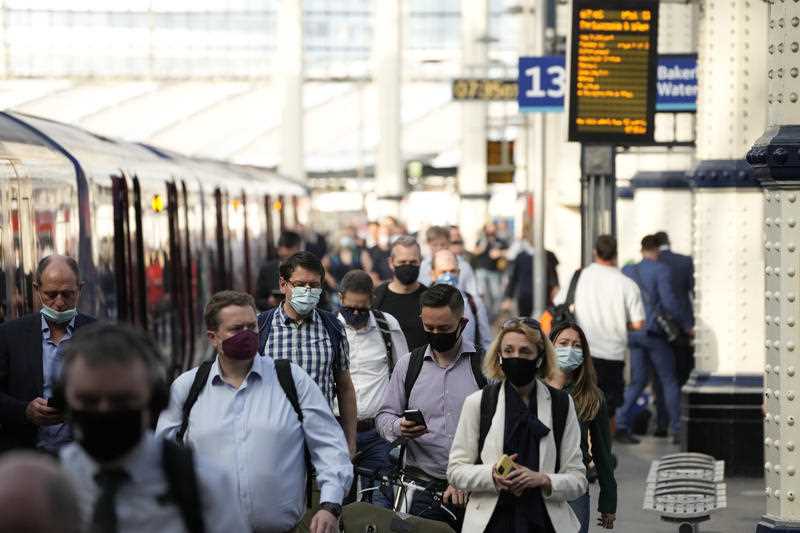 People wear face masks to curb the spread of coronavirus as they disembark from a train during the morning rush hour at Waterloo train station in London, Wednesday, July 14, 2021
