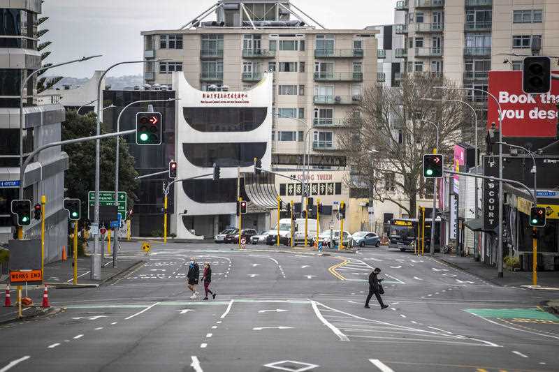 3 People cross nearly empty streets in the central business district of Auckland, New Zealand, Friday Aug. 27, 2021
