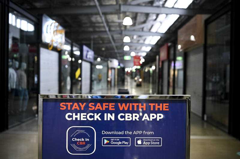 A sign recommends the use of the Check In CBR App at the Canberra Outlet Centre