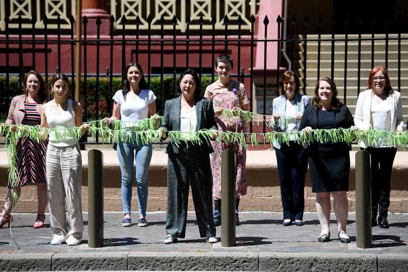 NSW Greens MP Jenny Leong (centre) along with fellow MP’s Felicity Wilson, Julia Finn and volunteers hang ribbons outside New South Wales Parliament House in Sydney, Thursday, October 21, 2021.