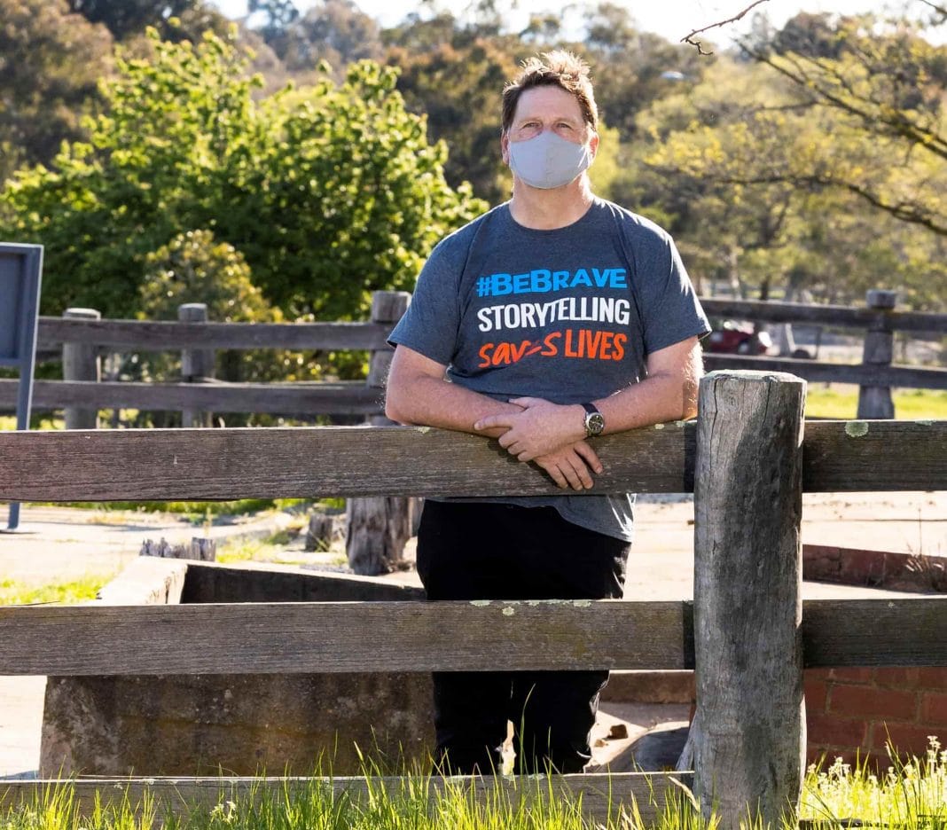 Mental Health Month ambassador Tim Daly leaning up against a fence in the outdoors