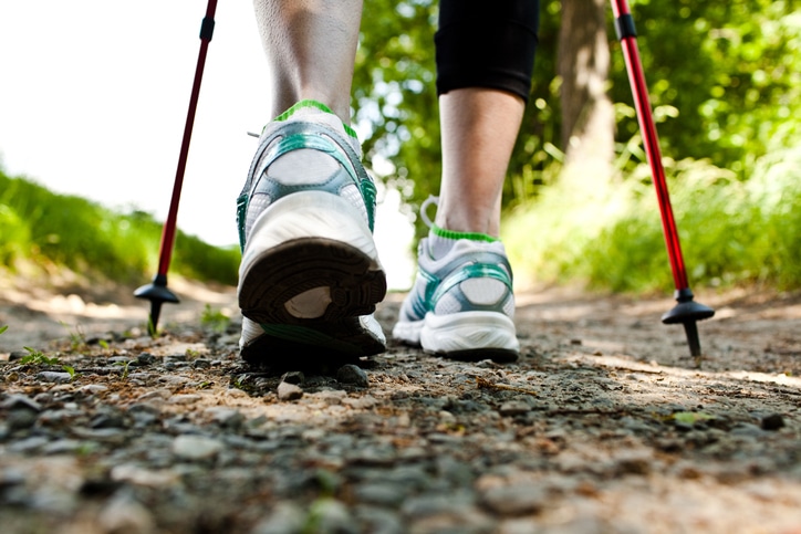 A person is seen walking in good walking shoes and holding two Nordic walking poles