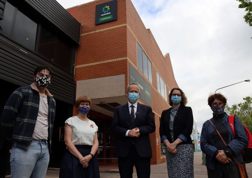 two federal politicians and three local residents all wearing face masks are seen standing in front of Braddon Centrelink shopfront