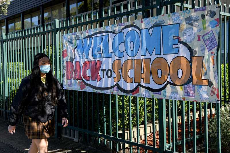 A welcome Back to School banner hangs on the fence as students in years 2-11 return to school at Fairvale High School in Sydney, Monday, October 25, 2021