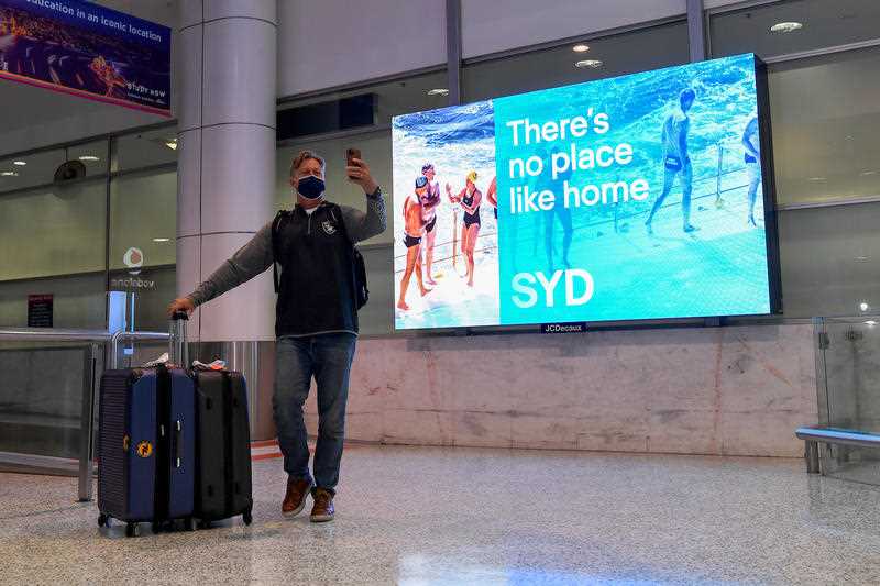A returning traveller arriving on one of the first quarantine-free international flights takes a selfie at Sydney International Airport, Monday, November 1, 2021