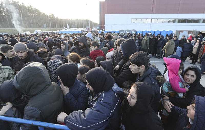 Migrants line up for food near a logistics center at the checkpoint 