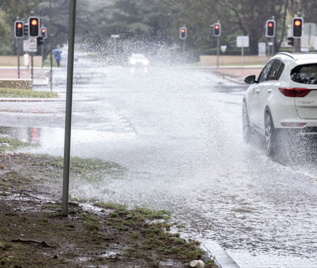 car driving through large puddle of rainwater on the road in Canberra
