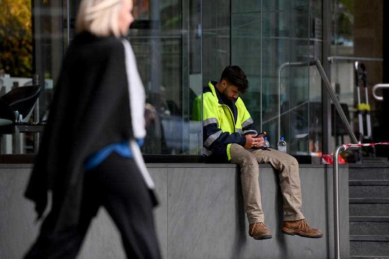 A tradesperson is seen on his phone in the central business district of Sydney