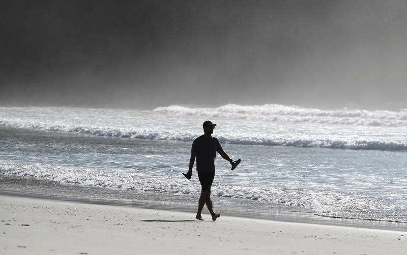 A lone man is seen walking along a beach