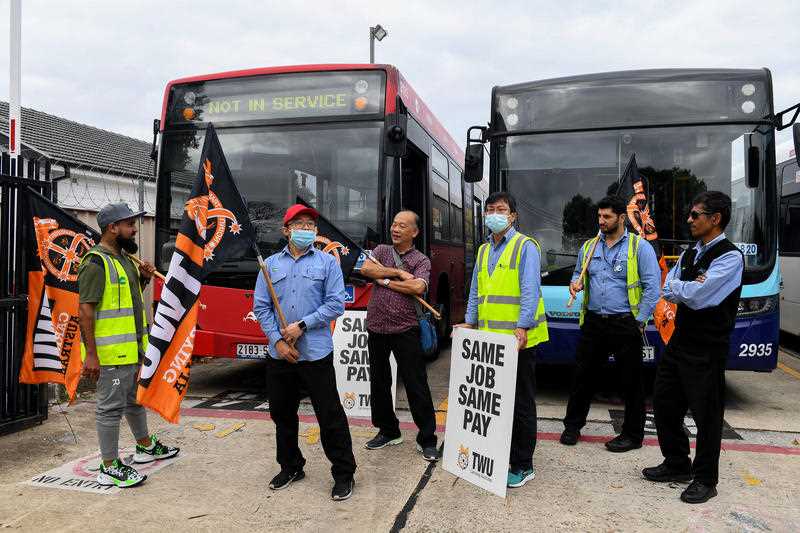 Bus drivers hold placards as they participate in a strike at Burwood Bus Depot in Sydney, Monday, December 6, 2021.