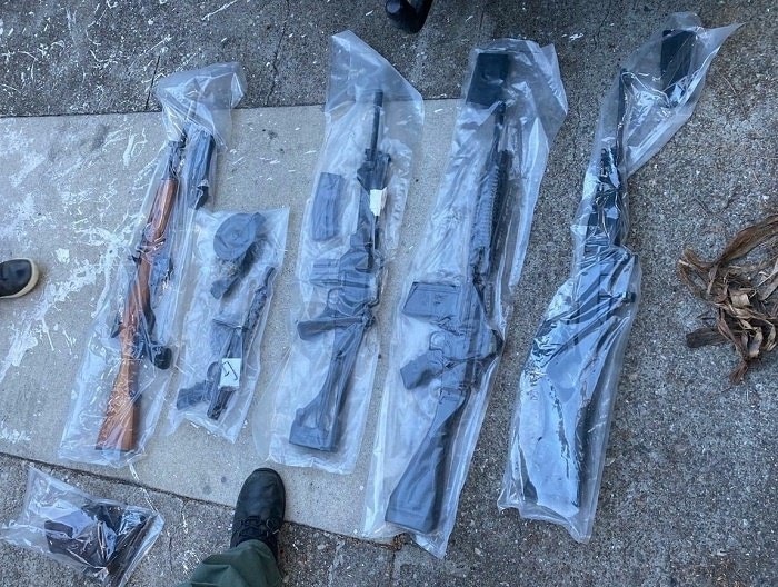 an array of several illegal firearms seized by police and bagged in plastic