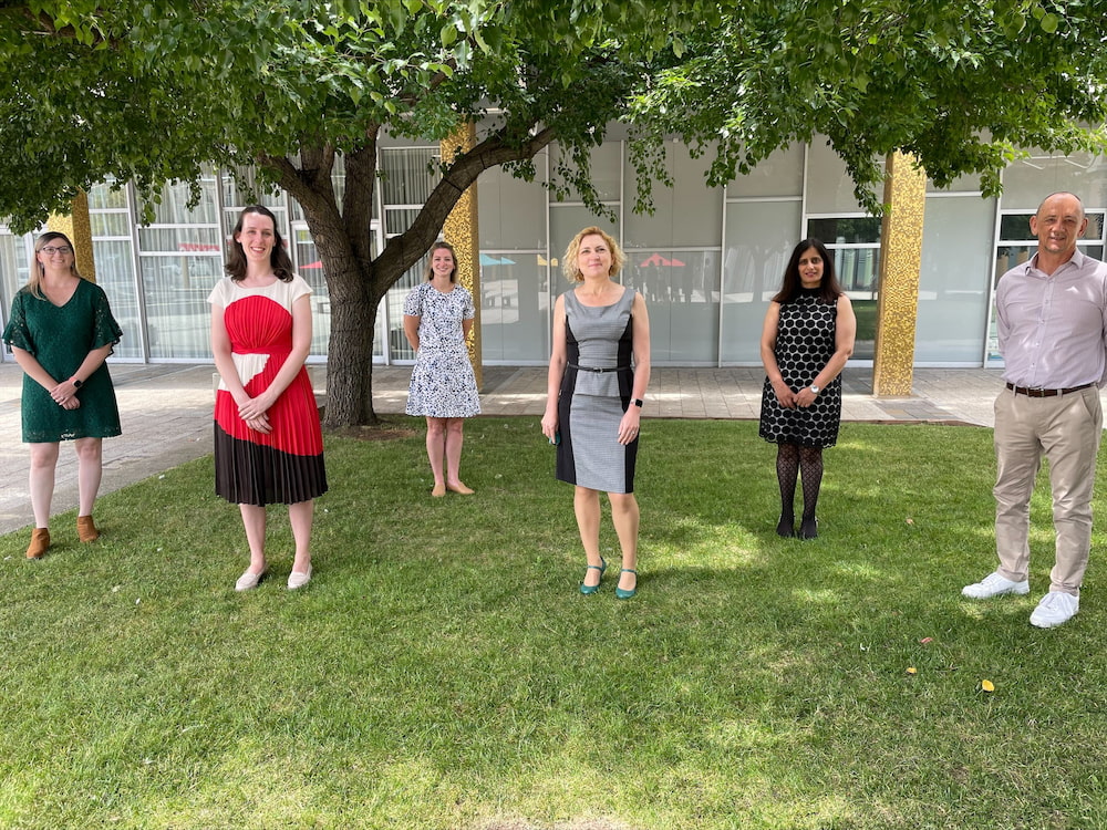 5 women and 1 man are seen standing socially distanced on lawns outside the ACT Legislative Assembly in Canberra