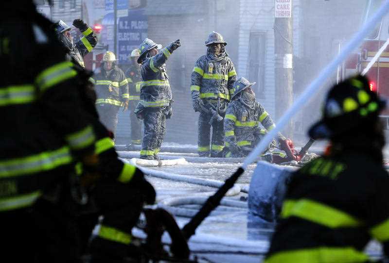Firefighters are covered with ice from water sprayed from their hoses as they work to contain a fire in the Bronx section of New York,