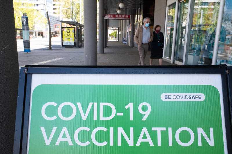 2 Residents walk past a pharmacy offering COVID-19 vaccination in Canberra