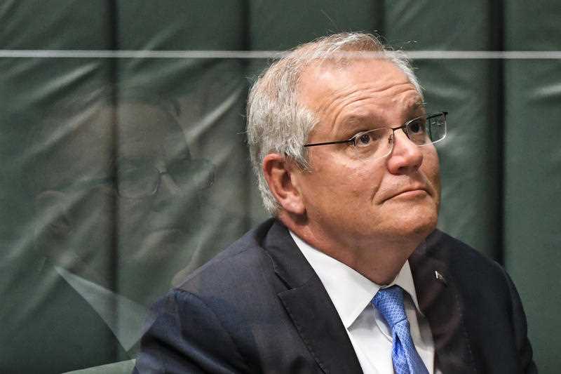 Australian Prime Minister Scott Morrison reacts as Australian Opposition Leader Anthony Albanese is seen reflected in a perspex screen during House of Representatives Question Time at Parliament House in Canberra