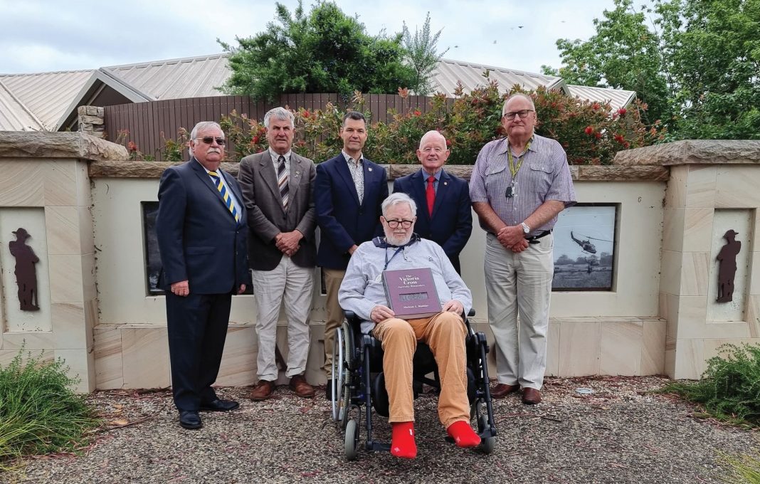 Victorian Cross recipient Colonel Adrian Roberts is seen in a wheelchair flanked by five ex-servicemen