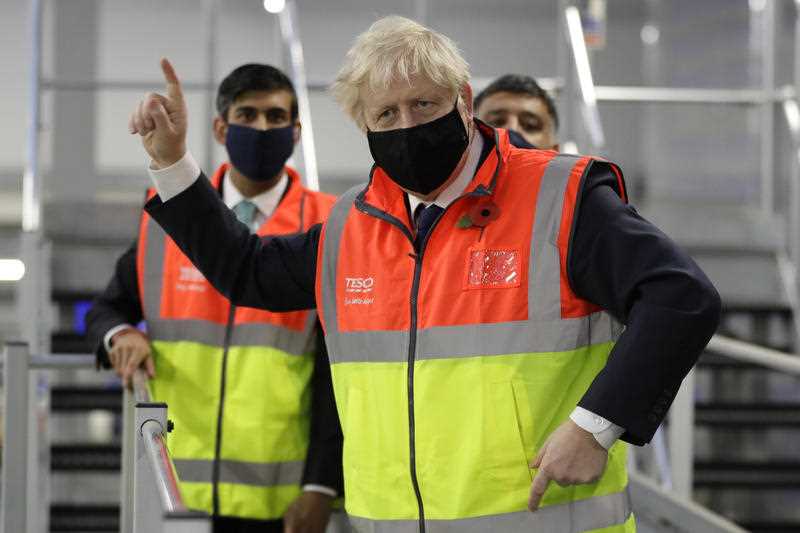 In this Nov. 11, 2020 file photo Britain's Prime Minister Boris Johnson, and Chancellor Rishi Sunak during a visit to a tesco.com distribution centre in London.