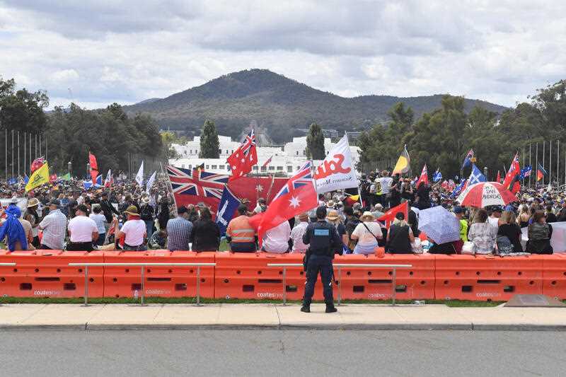 Thousands of protesters with flags are seen during an anti-vaccination rally outside Parliament House in Canberra, Saturday, February 5, 2022