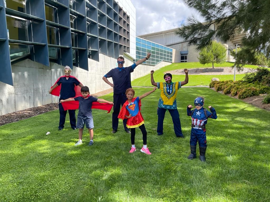 Jessie Holberton, Assistant Director of Nursing, COVID-19 Services – testing and vaccination at Canberra Health Services, with her colleagues Brendan Higgins and Amanda Nwoye, and three superheroes who dropped in to help, Alex, Zara, and Spencer. Photo provided.