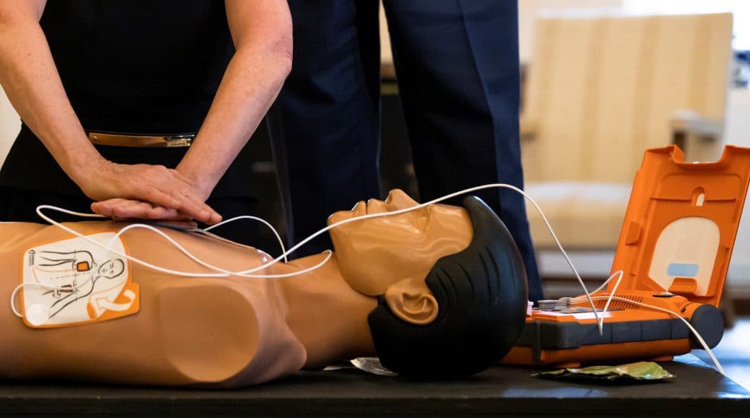 A person is seen demonstrating a heart defibrillator on a dummy