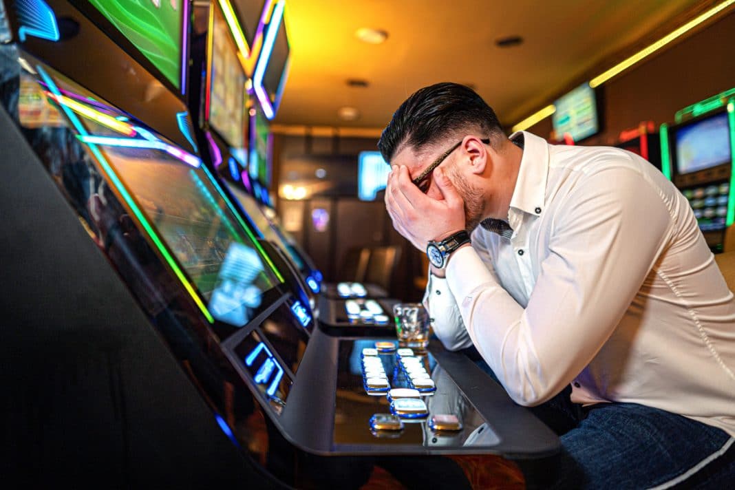 Worried man losing his money on a poker machine