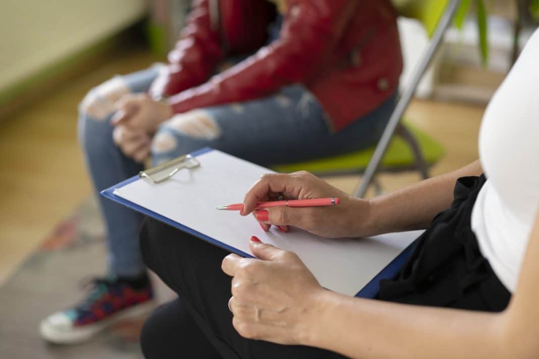 a counsellor is seen taking notes while speaking with a young person