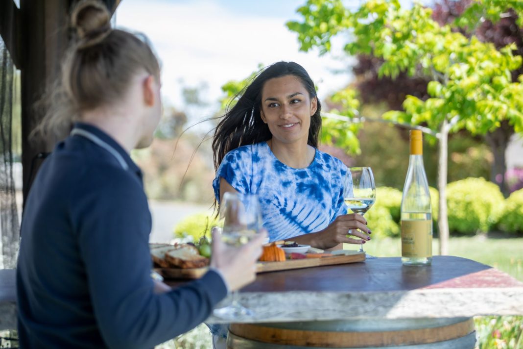 Four young people enjoying food and wine at a winery in the Queanbeyan-Palerang region of NSW