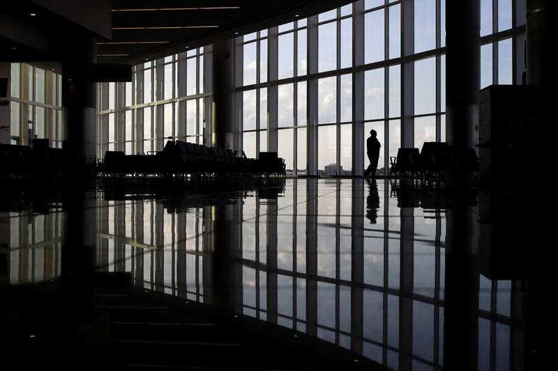a woman looks through a window at a near-empty terminal at an airport
