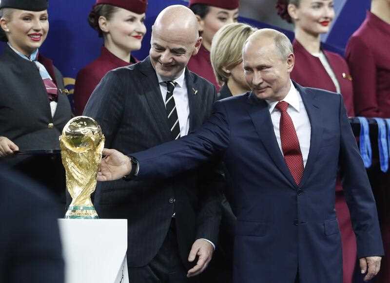 Russian President Vladimir Putin touches the World Cup trophy as FIFA President Gianni Infantino stands beside him, at the end of the final match between France and Croatia at the 2018 soccer World Cup in the Luzhniki Stadium in Moscow
