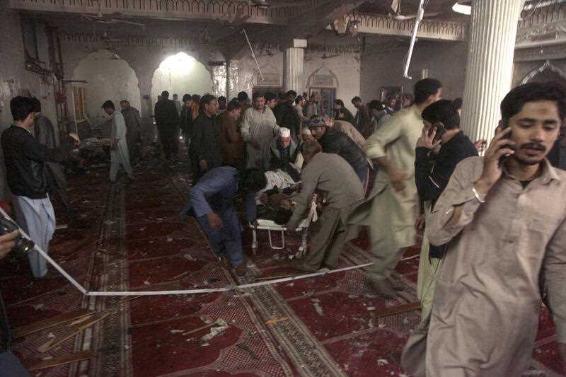 Rescue workers and volunteers remove a body from the site of bomb explosion in a mosque in Peshawar, Pakistan, Friday, March 4, 2022
