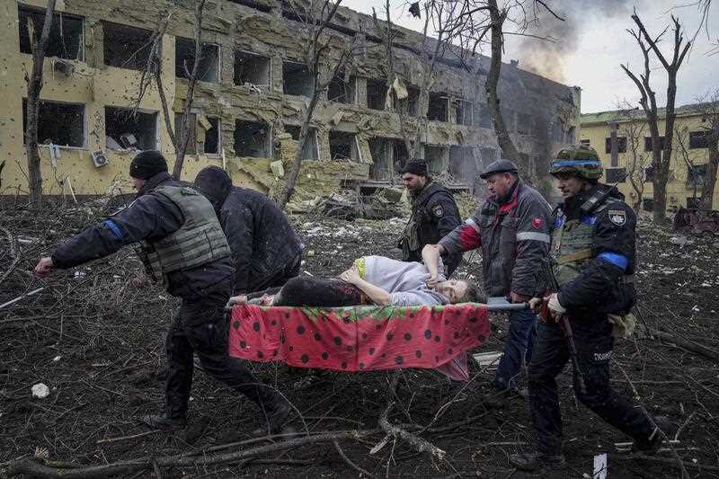 Ukrainian emergency employees and volunteers carry an injured pregnant woman from the damaged by shelling maternity hospital in Mariupol, Ukraine, Wednesday, March 9, 2022.