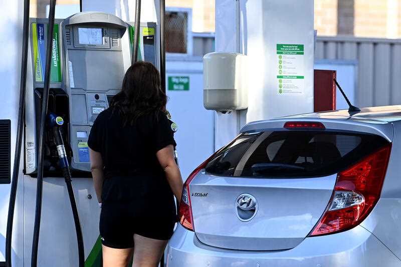 A woman fills her car with petrol at a petrol station