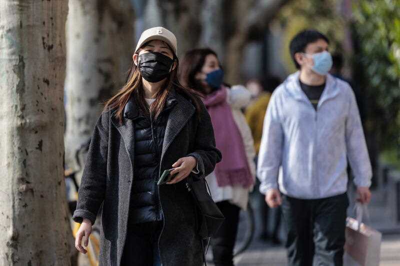 People wearing masks walk around Shanghai, China, 23 March 2022