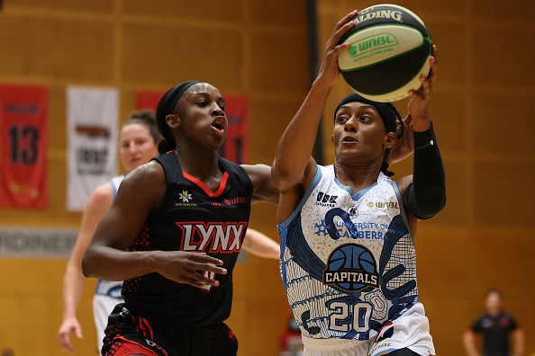 professional women's basketball player Brittney Sykes of the UC Capitals drives to the basket against Jackie Young of the Perth Lynx