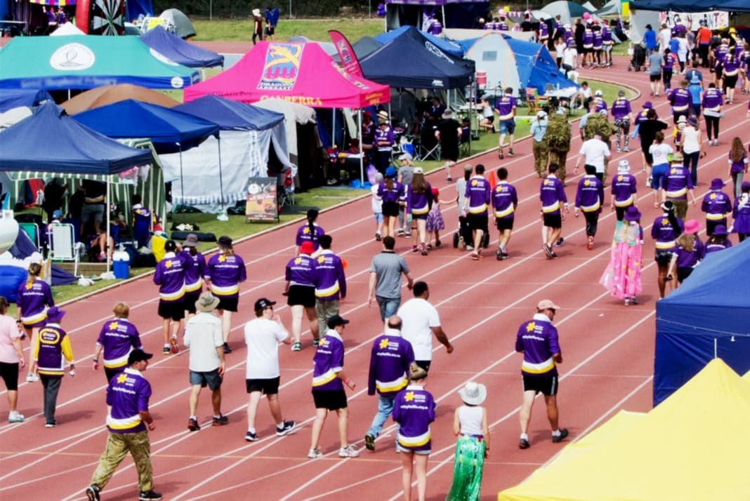 people in purple Relay 4 Life shirts are seen walking the circuit at the AIS Athletics Track